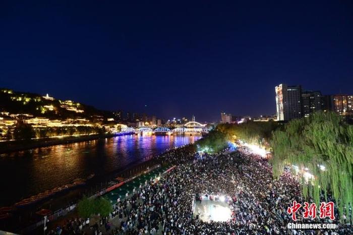 夕阳西下，夜幕降临时分，黄河岸边的广场上“黄河大合唱”响彻夜空。图/视觉中国