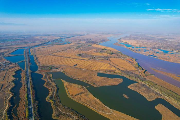 从空中俯瞰，蓝天下蜿蜒的黄河与农田、湿地相映成景。