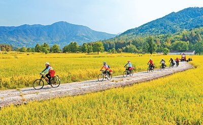 骑行爱好者在安徽省黄山市黟县塔川国家森林公园的田间道路上骑行，欣赏乡村美景。　　许家栋摄（人民图片）