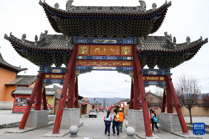   11月18日，在甘肃省陇南市宕昌县哈达铺镇上街村，学生们穿过红军门进入红军街去上学。新华社记者 郎兵兵 摄