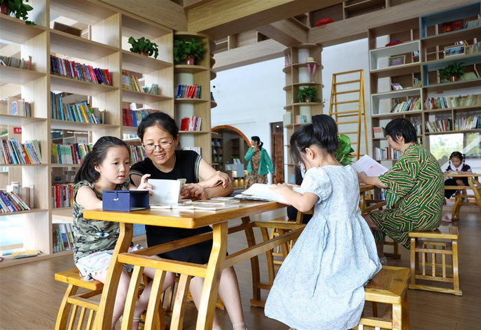 谷城县石花镇将军山村，志愿者陪伴孩子们在村农耕书屋看书。