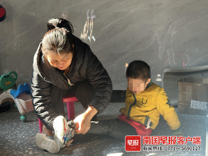 ▲何女士帮鑫泽穿鞋。武宣县融媒体中心供图