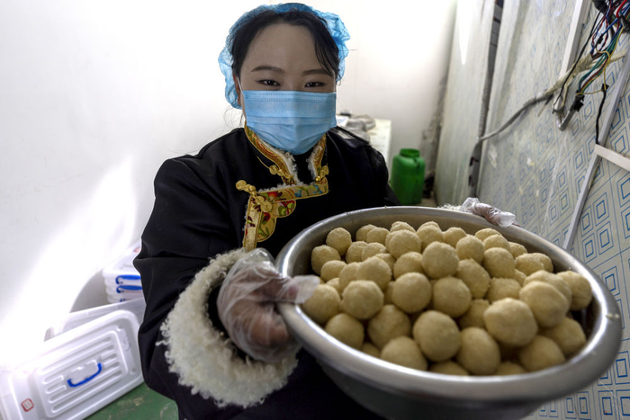 ↑11月28日，在基地就业的牧民白玛卓嘎展示刚刚做好的奶制品。