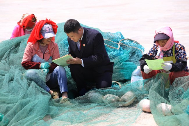 灌云县检察院公益诉讼检察官走访村民了解海漂垃圾治理效果。