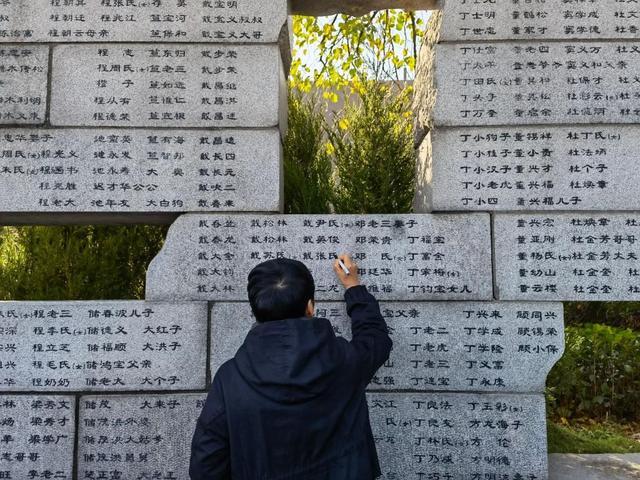 已故南京大屠杀幸存者常志强的女儿常小梅为“哭墙”上家人的姓名“描新”。 新华社记者 邱冰清 摄