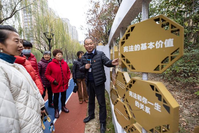 2023年12月4日，在浙江省湖州市吴兴区龙泉街道祥和社区法治公园，志愿者在给居民讲解宪法知识。新华社