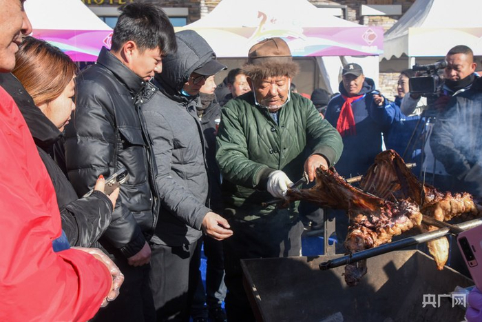 游客在美林谷滑雪场品尝烤全羊（央广网发  哨音  摄）