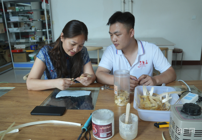 谷穗现场指导残疾人学员处理草编原料资料图（央广网记者  王艺霖  摄）