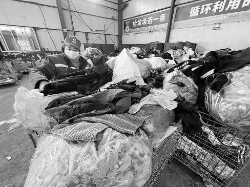 　　分拣中心内，工作人员对回收袋内的衣物进行初步分拣。 记者 张楠 摄