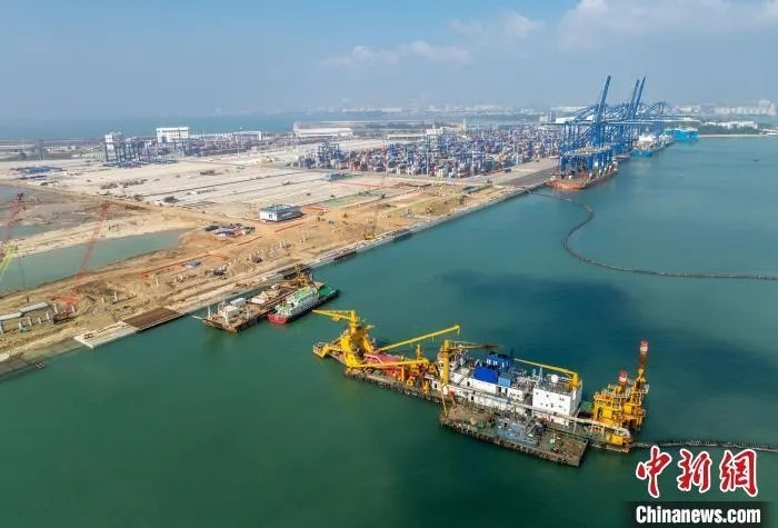 11月14日，洋浦区域国际集装箱枢纽港扩建工程正在紧张施工，远处的海南洋浦港国际集装箱码头作业繁忙。骆云飞摄