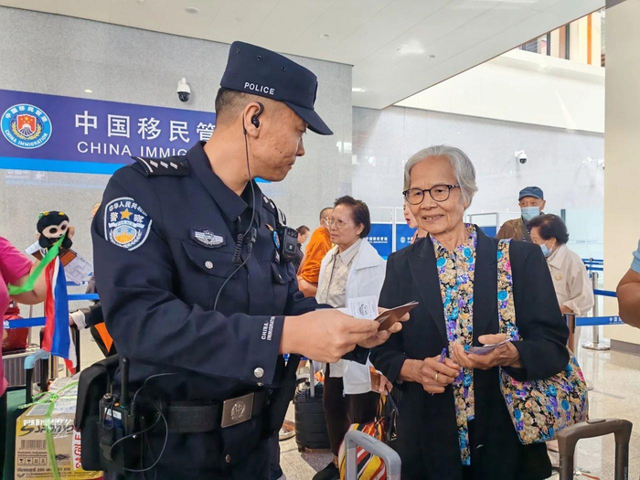 △磨憨边检站移民管理警察查验旅客证件。