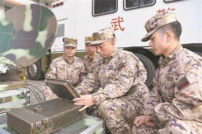 武警四川总队二级警士长秦春龙（右二）为战友讲解设备操作要领。王百越摄