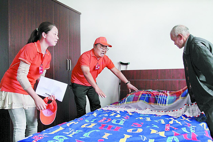     志愿者帮养老院的老人整理床铺    资料图片