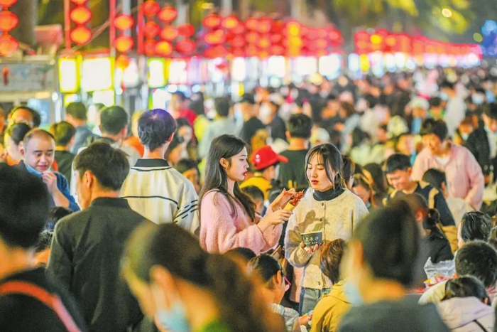 海大南门夜市灯火通明，人群熙熙攘攘，各档口前排起长队，就餐区座无虚席，展现出一派热闹景象。苏弼坤 摄