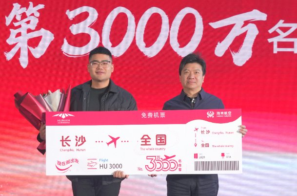 湖南机场集团党委书记、董事长邱继兴为第3000万名幸运旅客芮海利颁发机票并送上鲜花。