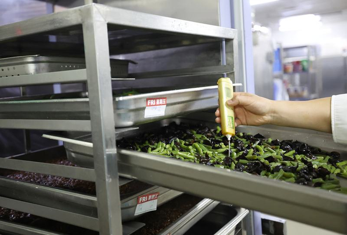 制作好的菜品需要放置在过渡冷库，工作人员检测菜品温度。新京报记者 陶冉 摄