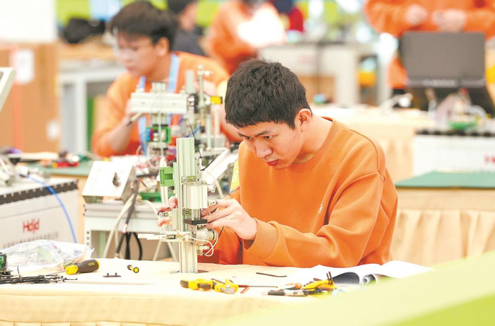机电一体化项目比赛现场，选手全神贯注组装机械。