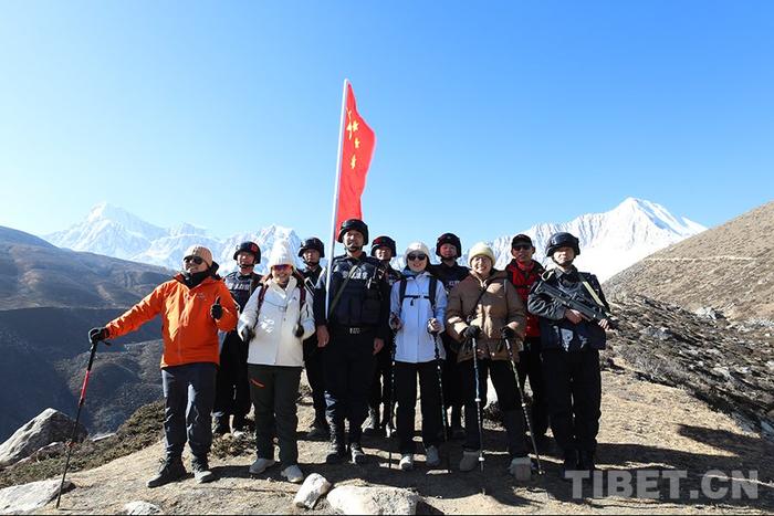 图为色边境派出所移民管理警察与游客一起在雪山之下合影