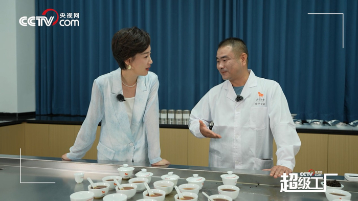 图为八马茶业乌龙茶事业部产品专家林金俗向央视网主持人常婷介绍评茶师的工作流程