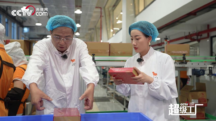 图为八马茶业总工程师、中国制茶大师林荣溪向央视网主持人常婷介绍八马茶业第七代智能化生产线