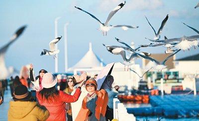 青海湖是国家级自然保护区，也是国家5A级旅游景区，图为游客在青海湖二郎剑景区游玩。新华社记者 张龙摄