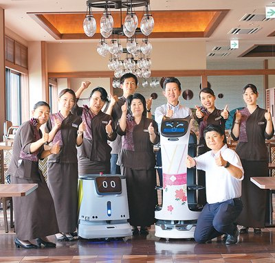 日本餐厅经营者与送餐机器人“贝拉”和清洁机器人CC1合影。采访对象供图