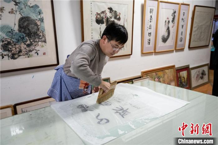 白彦斌正在手工装裱字画。韦亮 摄