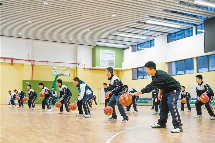 雁塔区第四中学的学生们在体育馆进行篮球运球训练。