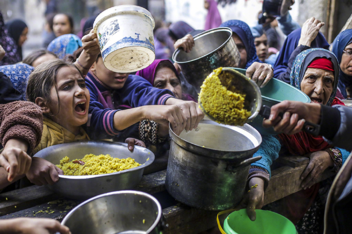 12月27日，巴勒斯坦人在加沙城领取救济食物。（图源：新华社）