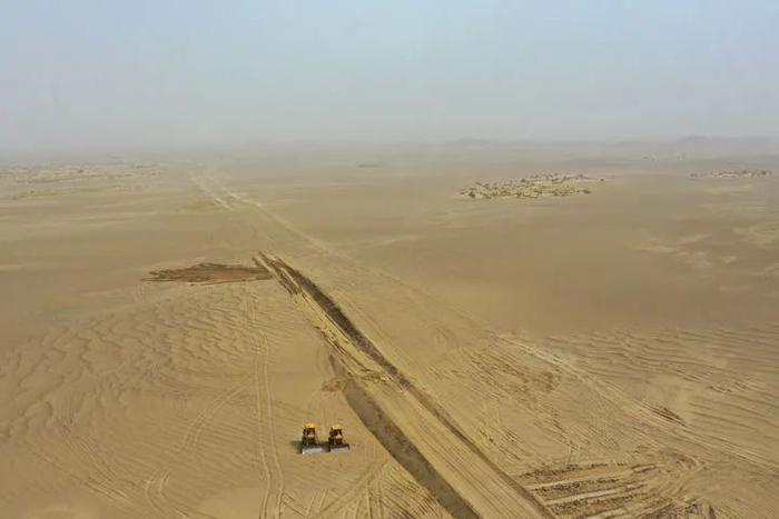2024年6月17日，在新疆和田地区民丰县亚瓦通古孜乡，推土机推平沙包通路（无人机照片）。新华社记者 丁磊 摄
