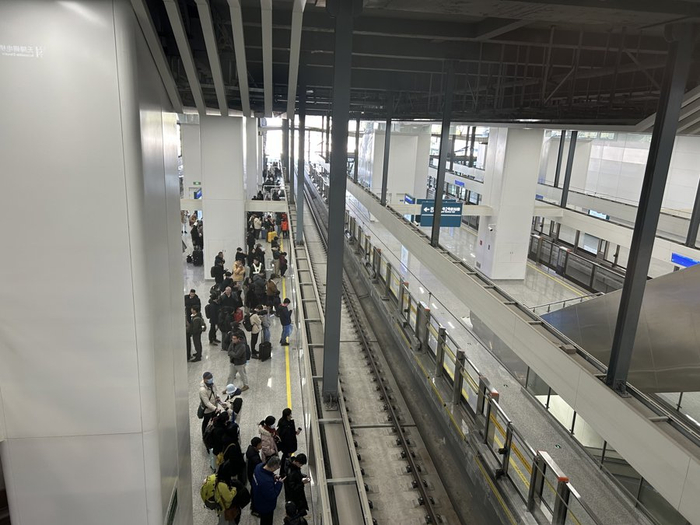 在市域机场线虹桥2号航站楼站，不少市民在屏蔽门前排起队，还有新的乘客陆续加入。
