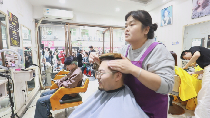 　　晓华在给顾客理发，店门口排满了人