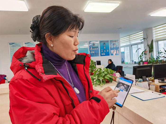 玉桥东里南社区党总支书记胡海燕展示新版电梯阻车器系统，可以从手机上实时看到电梯内画面。新京报记者 张璐 摄