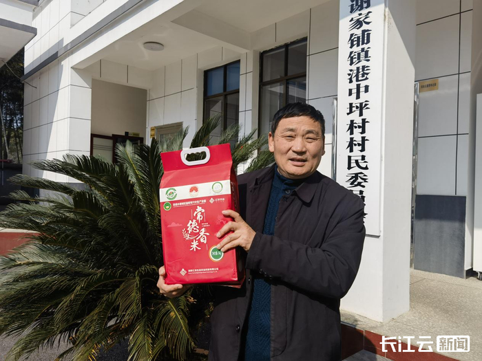 湖南省港中坪村党支部书记段德喜向记者展示本地的优质稻米。