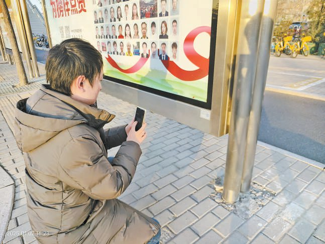 东单路口南公交站亭的二维码位置太低，乘客需要弯腰蹲下才能从正面扫描。 成进羽摄