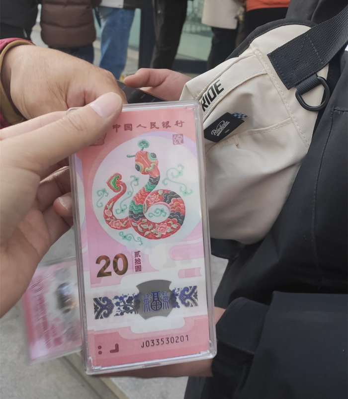 消费者展示刚刚兑换到的蛇年纪念币。聂国春/摄