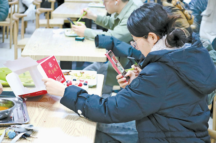 学生在给学校食堂推出的限量蛋糕拍照