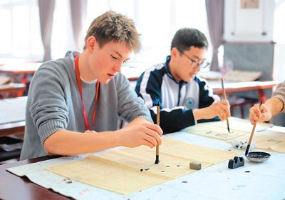 图为活动期间，来自美国得克萨斯州圣史蒂芬圣公会学校的学生查尔斯·钱宁·达根（左）在河北衡水中学学习书法。陈康 摄