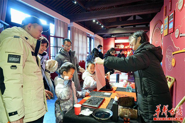 游客带着孩子在湖南体验区内体验非遗项目。邓存存 摄