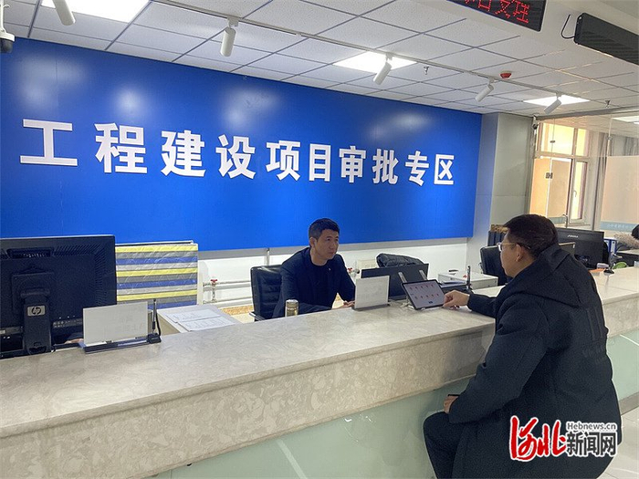 2024年12月18日，张家口市经开区数政局，一位办事群众（右）咨询行政审批相关事项。 河北日报记者 魏 雨摄