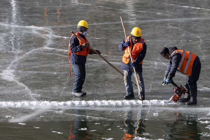 取冰师傅手持冰机与冰具在冰面上切割、开凿冰块。