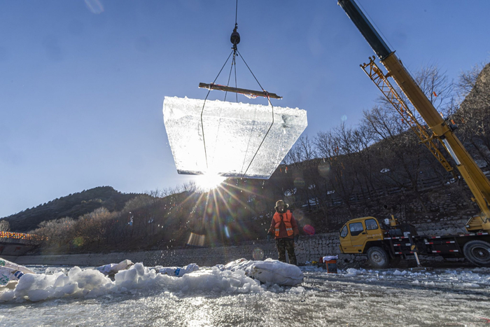 整块冰被吊起，即将装车运往冰灯展示区域进行冰灯制作。