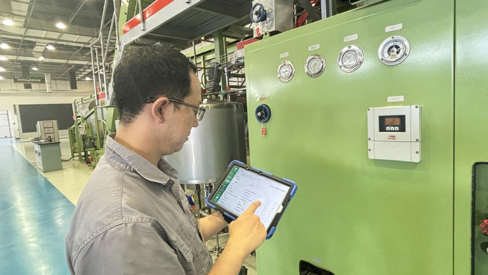 青岛卷烟厂制丝线上，工作人员使用PAD设备执行巡检任务。王培琛 摄