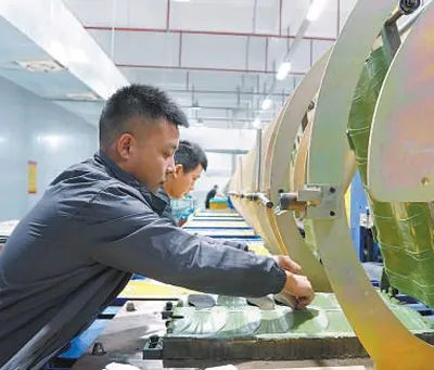 泉州市星达鞋服材料有限公司员工在高温热压塑形生产线作业。（图为人民日报记者戴林峰 摄）