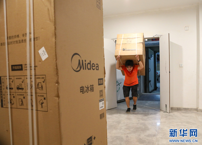 在云南省西双版纳傣族自治州景洪市一小区内，家电商场工作人员正在为顾客送货。新华网发（李云生 摄）