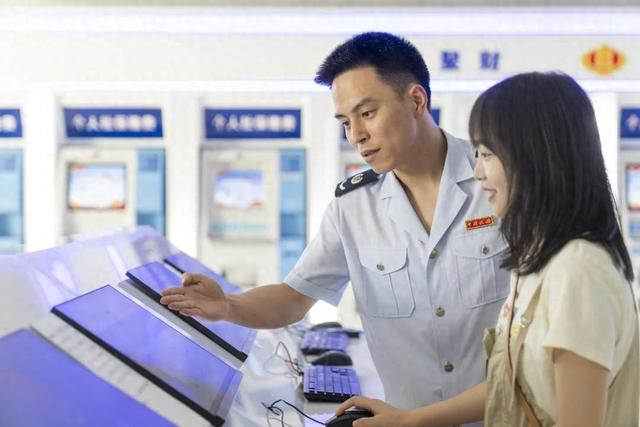 国家税务总局重庆市渝北区税务局第一税务所工作人员在自助办税区辅导纳税人使用电子税务局填报相关信息。郭睿 摄