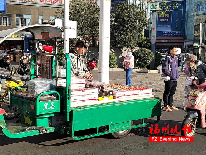 茶亭街路口，商贩将车厘子摆在三轮车上叫卖。