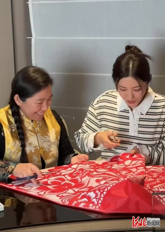 李娜在教曾黎剪纸。网络视频截图