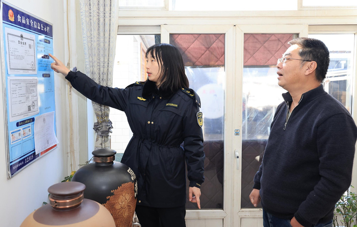 市场监管所工作人员在高记酒坊和高志成交流。冯铁飞/摄