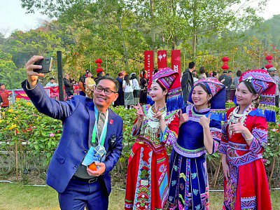     1月17日，在广西南宁古岳坡文化艺术村，外宾同身着全民族服饰的当地姑娘们合影留念。本报记者 闫丛笑摄/光明图片